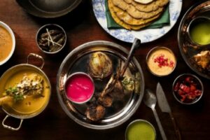 A vibrant spread of Manali local cuisine featuring grilled meats, flatbreads, colorful sauces, and side dishes on a wooden table